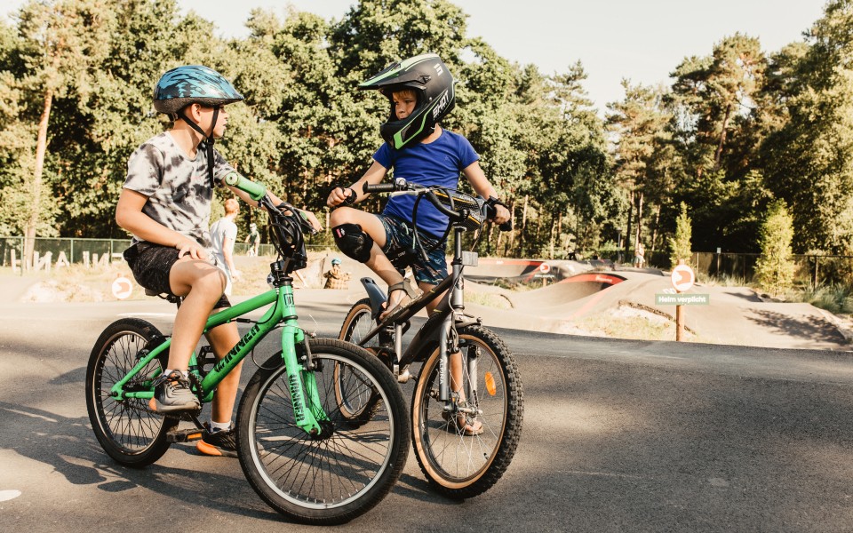 Camping-de-kleine-wolf-faciliteit-pumptrack-jongens-op-fiets-kijken-elkaar.jpg